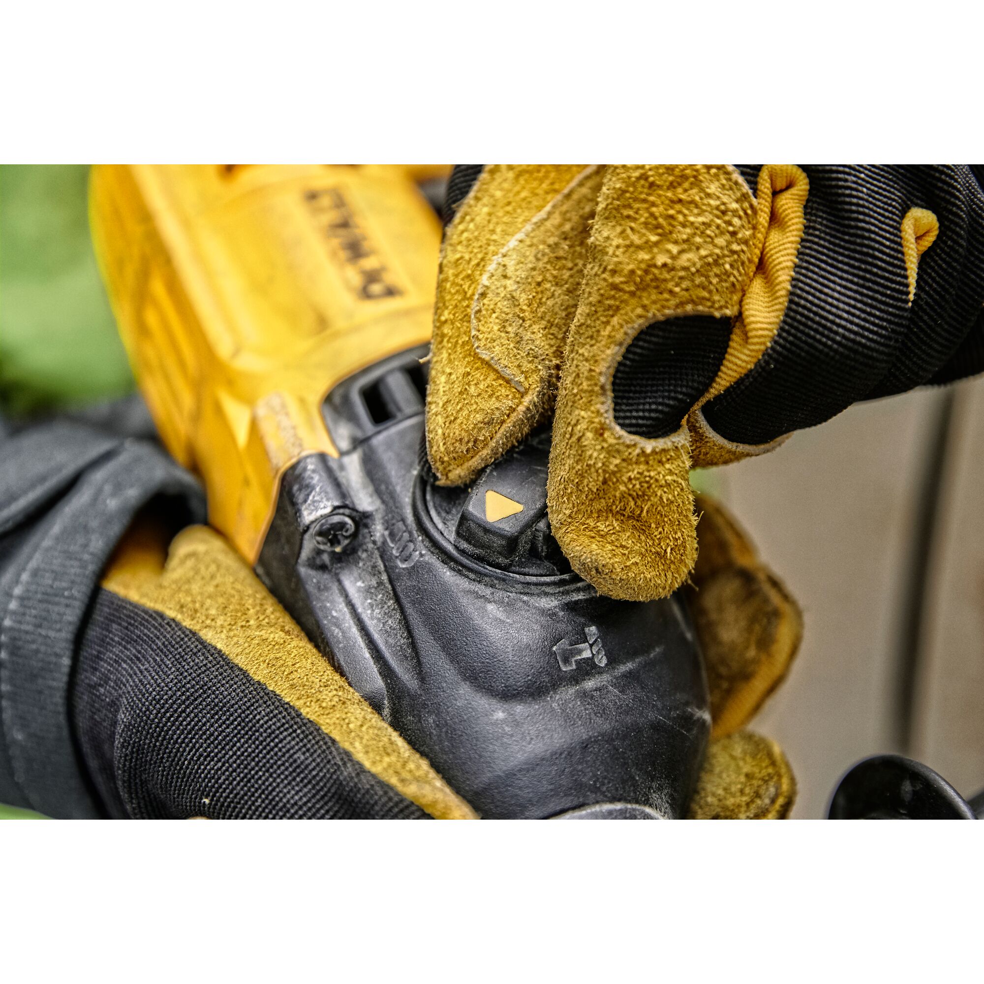 Close-up of a person wearing yellow and black work gloves adjusting a mode selector switch on a DEWALT power tool.