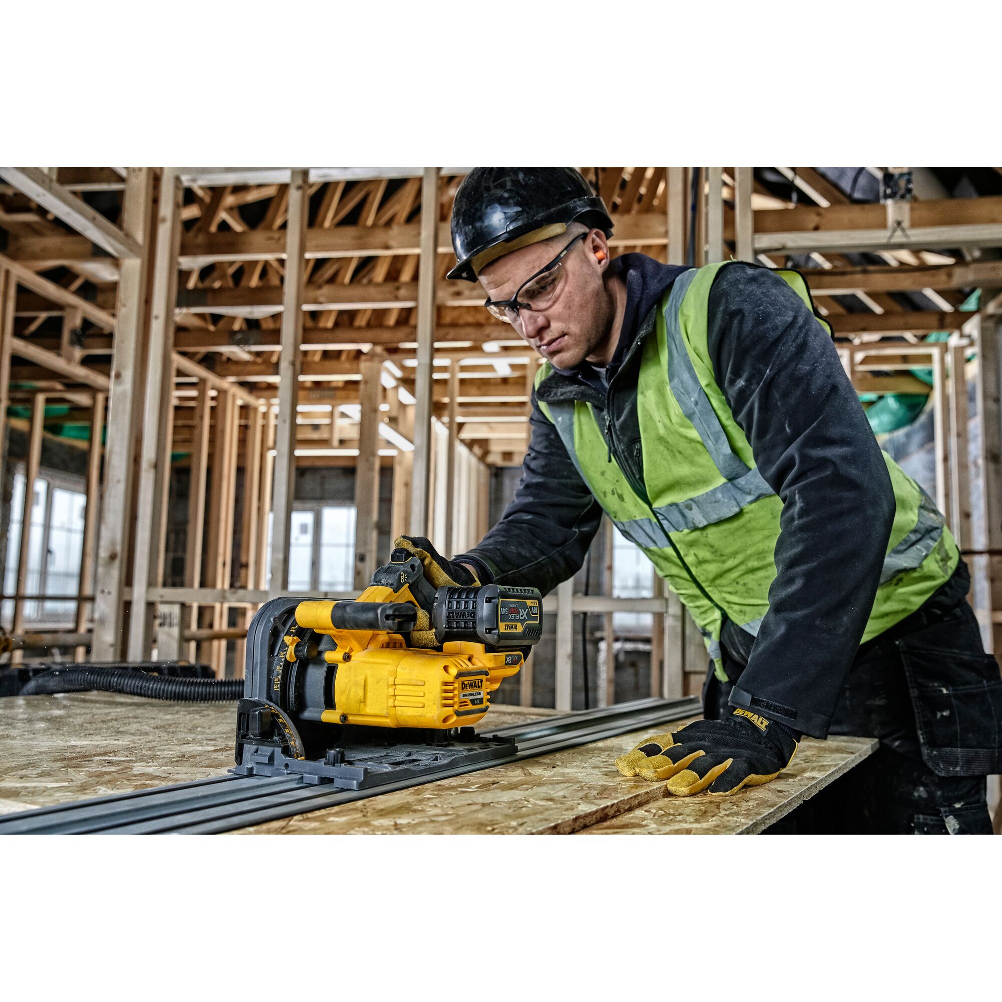 Worker uses a DEWALT DCS520NT power tool to cut wood at a construction site with unfinished framing.